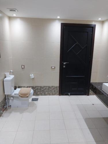 a bathroom with a toilet and a black door at Beach safari nubian resort in Marsa Alam City