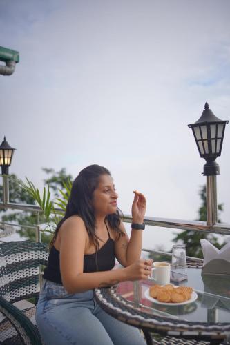a woman sitting at a table with a plate of food at Sangam by Stotrak, Jhula Ghar Mussoorie in Mussoorie