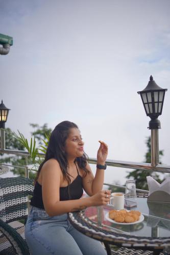 a woman sitting at a table with a plate of food at Sangam by Stotrak, Jhula Ghar Mussoorie in Mussoorie