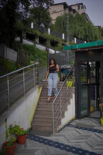 a woman standing on the stairs at a bus stop at Sangam by Stotrak, Jhula Ghar Mussoorie in Mussoorie