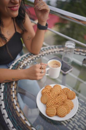 a woman sitting at a table with a plate of cookies at Sangam by Stotrak, Jhula Ghar Mussoorie in Mussoorie