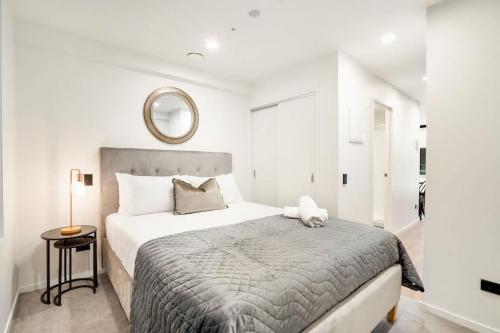 a bedroom with a large bed and a mirror at Stunning Architecturally Designed Studio in CBD - Pool Gym Sauna in Auckland