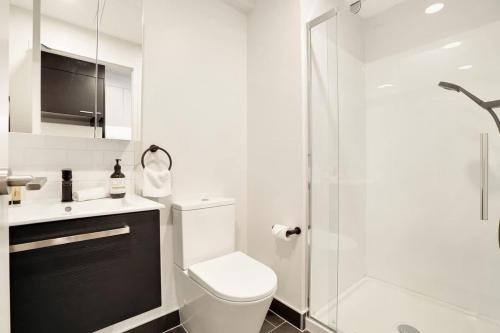a white bathroom with a toilet and a shower at Stunning Architecturally Designed Studio in CBD - Pool Gym Sauna in Auckland
