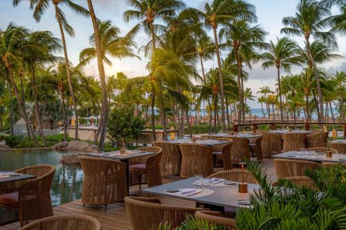 a restaurant with tables and chairs and palm trees at Hilton Aruba Caribbean Resort & Casino in Palm-Eagle Beach