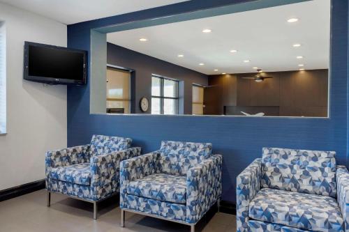 a waiting room with blue chairs and a mirror at Avion Inn Near LGA Airport, an Ascend Collection Hotel in Queens