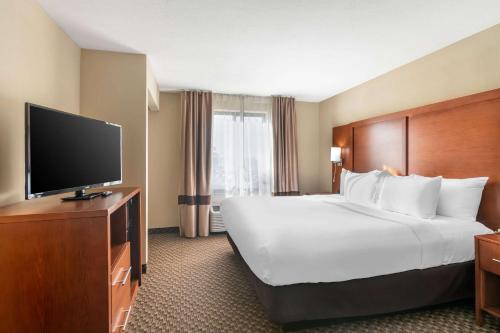a hotel room with a large bed and a flat screen tv at Comfort Suites Manhattan in Manhattan