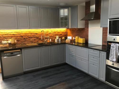 a kitchen with white cabinets and a brick wall at Cannock Chase Guest House - Modern Super Spacious Renovated home for 6 guests in Huntington