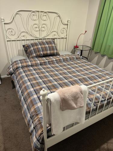 a white bed with a plaid blanket and pillows at Love House in Auckland
