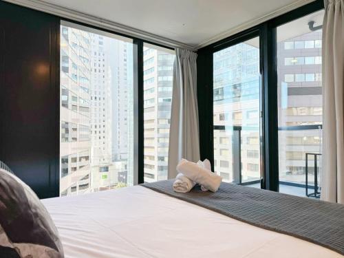 奥克兰Modern 2 Bedroom Beside Skytower & Queen St in The Heart of CBD的窗户间里一张带毛巾的床