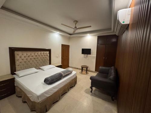 a bedroom with a bed and a chair in it at City view hotel lawrance road in Lahore