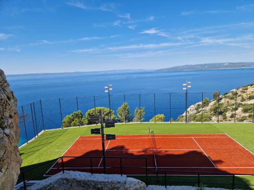 a tennis court with the ocean in the background at Kuk Oaza Luxury Villas in Makarska