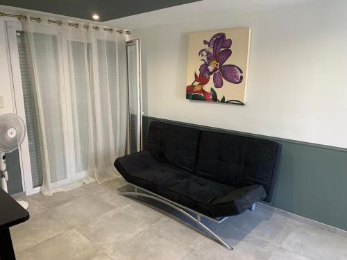 - un canapé noir dans une pièce ornée d'une peinture murale dans l'établissement Studio idéal pour travail ou vacances dans le sud, à Fos-sur-Mer