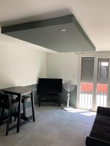 un salon avec une table et une télévision dans l'établissement Studio idéal pour travail ou vacances dans le sud, à Fos-sur-Mer
