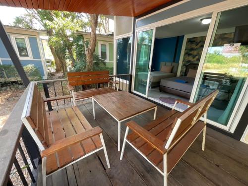 a porch with two benches and a table and chairs at Rayonghouse Resort in Rayong
