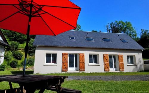 a red umbrella sitting on a table in front of a house at Gite Lahora Lait'colo de l'Izard - Appartement Panoramique in Arrens-Marsous