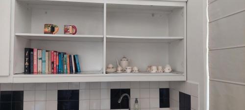 a kitchen shelf with books and cups and a sink at Colombo 07 Charming Home Stays in Colombo