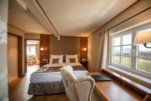 a bedroom with a bed and a desk and windows at Berghotel Eisenach in Eisenach