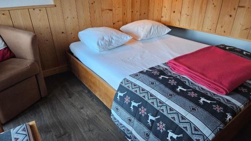 - un petit lit dans une chambre avec un canapé dans l'établissement Dvacances Résidence les tavaillons, à Mijoux