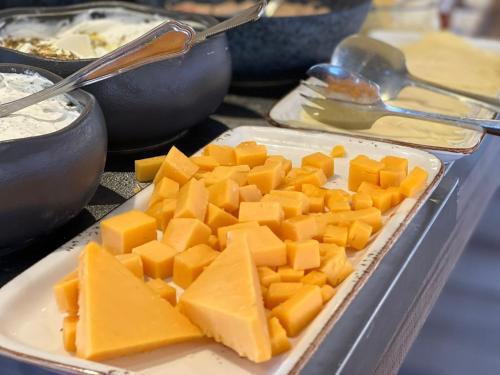 a plate of cheese on a table with other foods at Hotel Basel Tel-Aviv in Tel Aviv