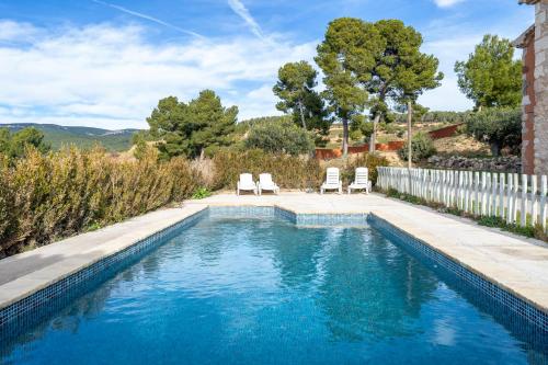a swimming pool with two chairs and a fence at Mas Colom-Can Cruset Agroturisme in Torrellas de Foix