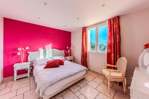 - une chambre aux murs roses avec un lit et une chaise dans l'établissement Domaine Soleu - piscine et vue montagnes, à Montauroux