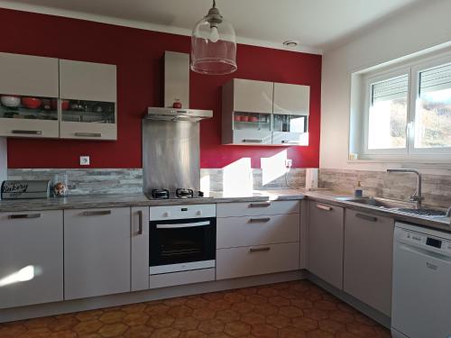 a kitchen with white cabinets and a red wall at Mon petit château in Pajay