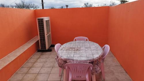une table et des chaises sur une terrasse avec un mur orange dans l'établissement 40 La Brossière, à Saint-André-Goule-dʼOie