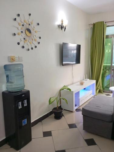 a living room with a tv and a plant in it at G-wel's Sun Sweet Apartment in Mombasa