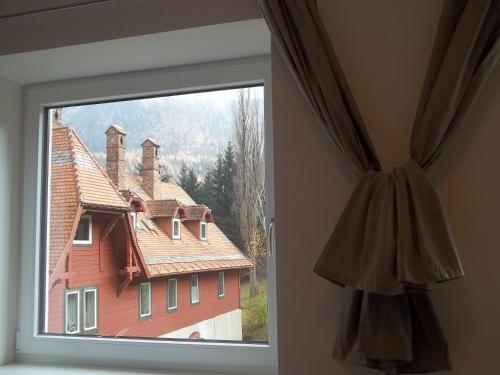 a window in a room with a large red house at Villa Wellspacher Luxury Apartments Semmering in Semmering
