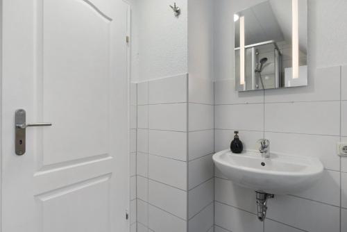 a white bathroom with a sink and a mirror at Klaus Lafrenz Petersdorf N°3 in Fehmarn