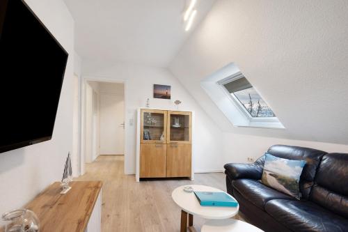 a living room with a leather couch and a tv at Klaus Lafrenz Petersdorf N°2 in Fehmarn