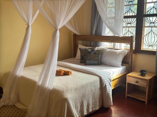 a bedroom with two beds with curtains and a window at Mahali House in Moshi