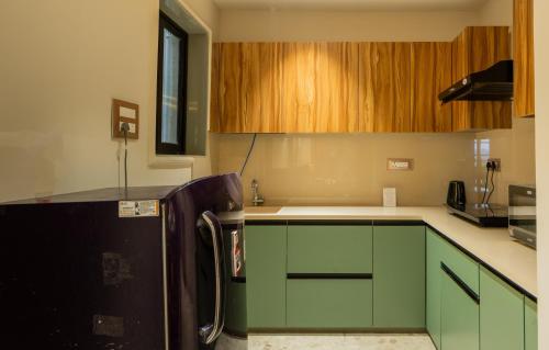 a kitchen with green cabinets and a black refrigerator at ELIVAAS 1 BHK with Rooftop Pool - Kamerios Skye in Nerul