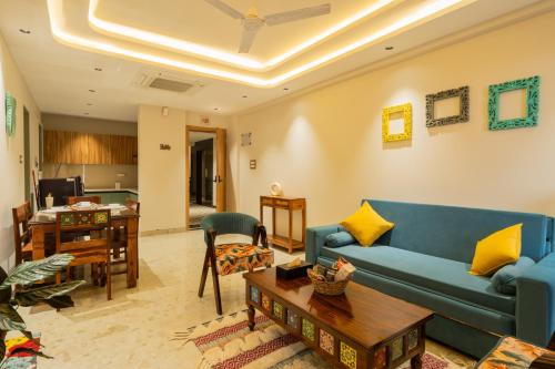 a living room with a blue couch and a table at ELIVAAS 1 BHK with Rooftop Pool - Kamerios Skye in Nerul
