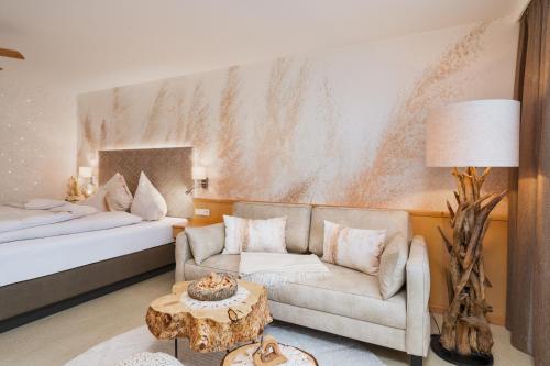 a hotel room with a couch and a bed at Fichtenwald-Ihr Boutique I Glück`s Hotel in Bad Füssing