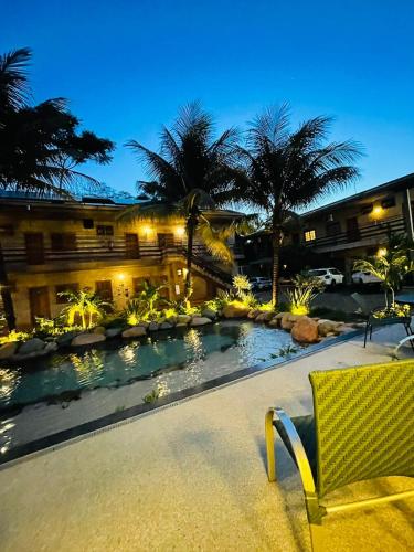 a resort pool with a chair and palm trees at Hotel Pousada Santa Rita in Ribeirão Preto