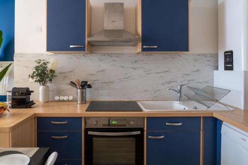 une cuisine avec des armoires bleues et un évier dans l'établissement Appartement central-Wifi-Netflix, à Montélimar