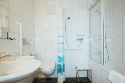 a bathroom with a toilet and a shower and a sink at Parkhotel Schwert in Weesen