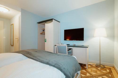 a bedroom with a bed and a desk with a television at Parkhotel Schwert in Weesen