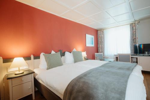 a bedroom with a large bed and a red wall at Parkhotel Schwert in Weesen