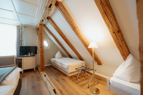a room with two beds and a desk in a attic at Parkhotel Schwert in Weesen