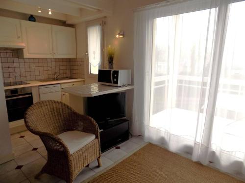 une cuisine avec une chaise et un four micro-ondes ainsi qu'une fenêtre dans l'établissement Saint Palais sur Mer - BEL APPARTEMENT 5 min à pied de la PLAGE du BUREAU, à Saint-Palais-sur-Mer