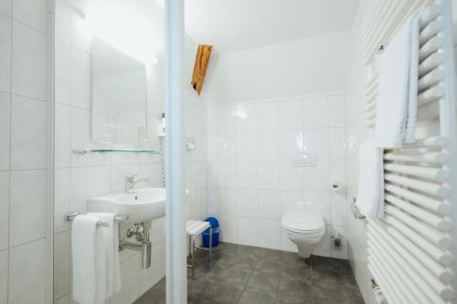 a white bathroom with a sink and a toilet at Parkhotel Schwert in Weesen