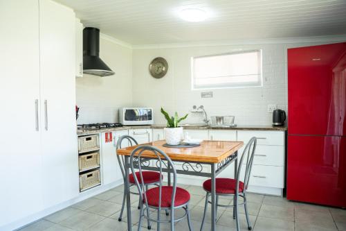 cocina con mesa de madera y nevera roja en Faraway Cottage 3 Gables Self catering Swellendam, en Swellendam