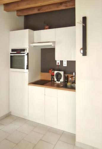 une cuisine avec des armoires blanches et un four à plaques de cuisson dans l'établissement Maison accueillante avec jardin à Selles-sur-Cher, à Selles-sur-Cher