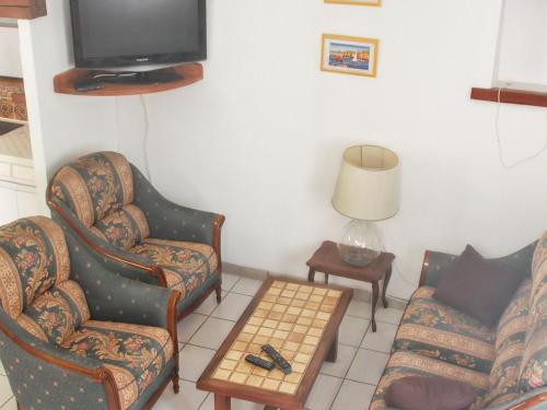 a living room with two chairs and a tv at Villa charmante à Sisteron avec piscine privée in Sisteron
