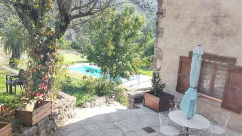 a patio with a table and an umbrella and a pool at Villa charmante à Sisteron avec piscine privée in Sisteron