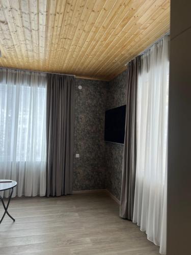 a living room with a wooden ceiling and curtains at Mestiakhedi in Mestia