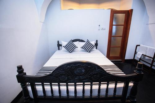 a bed with black and white pillows in a room at Villa 1908 in Dodanduwa