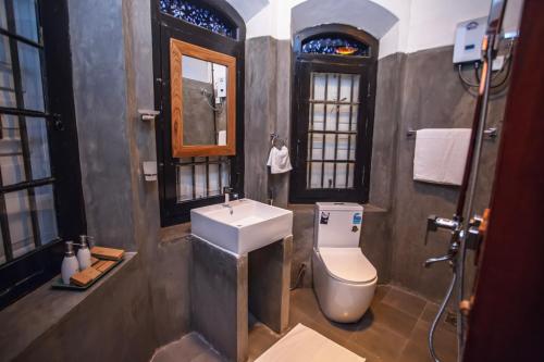 a bathroom with a toilet and a sink and window at Villa 1908 in Dodanduwa